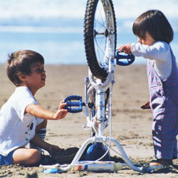 Deux enfants à la plage devant un vélo